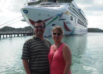 a man and woman standing in front of a cruise ship