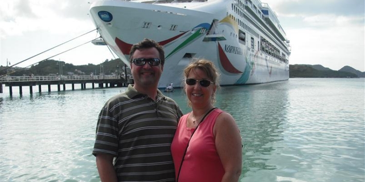 a man and woman standing in front of a cruise ship