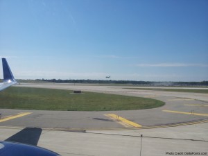 a runway with a plane flying in the sky