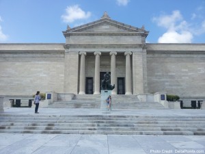 a stone building with columns and a statue with Glyptothek in the background