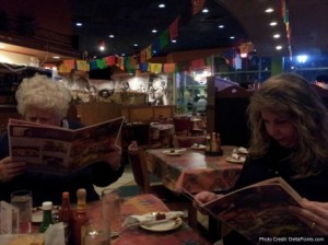 a group of people sitting at tables reading menus