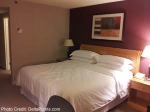 a bed with white sheets and a lamp on the side