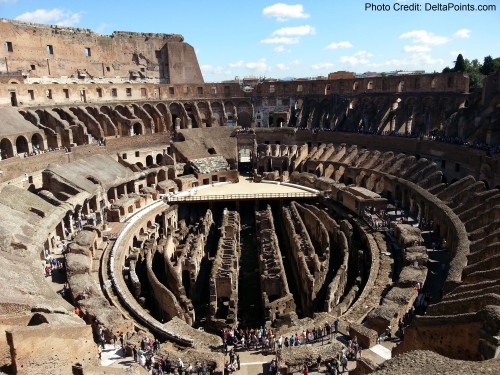 a group of people inside a large stone arena with Colosseum in the background