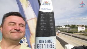 renespoints-infront-of-surf-board-with-arrival-flights-sxm-sunset-bar