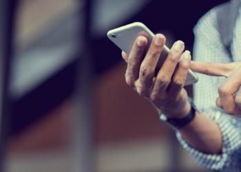 close up traveler backpacker man hand holding smartphone for checking flight online or search information on browser website about plan trip at destination , lifestyle concept