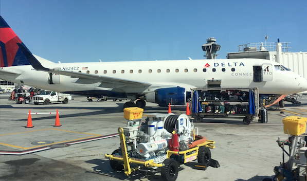 a white airplane with a cart and equipment on the ground