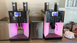 a group of coffee machines with pink lights
