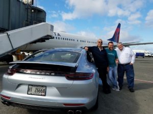 a group of men standing next to a car