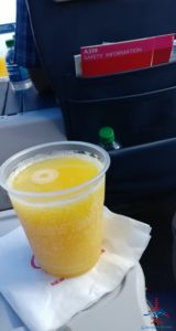 a hand holding a plastic cup with a yellow drink in it