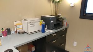 a desk with a printer and a flower vase