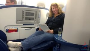 a woman sitting on a plane holding a tablet