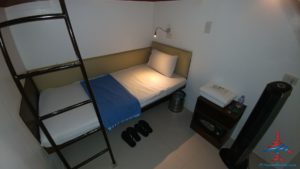 a bed with a blue blanket and a ladder