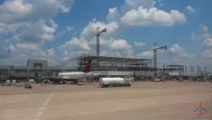 a large building with cranes and planes in the background