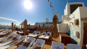 a deck with chairs and umbrellas on a cruise ship