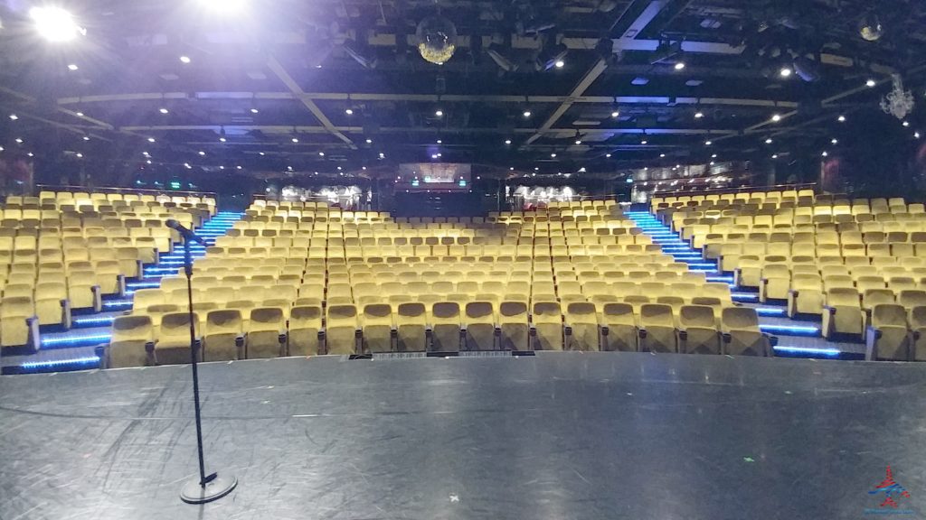 a stage with a microphone in front of a stage with yellow chairs