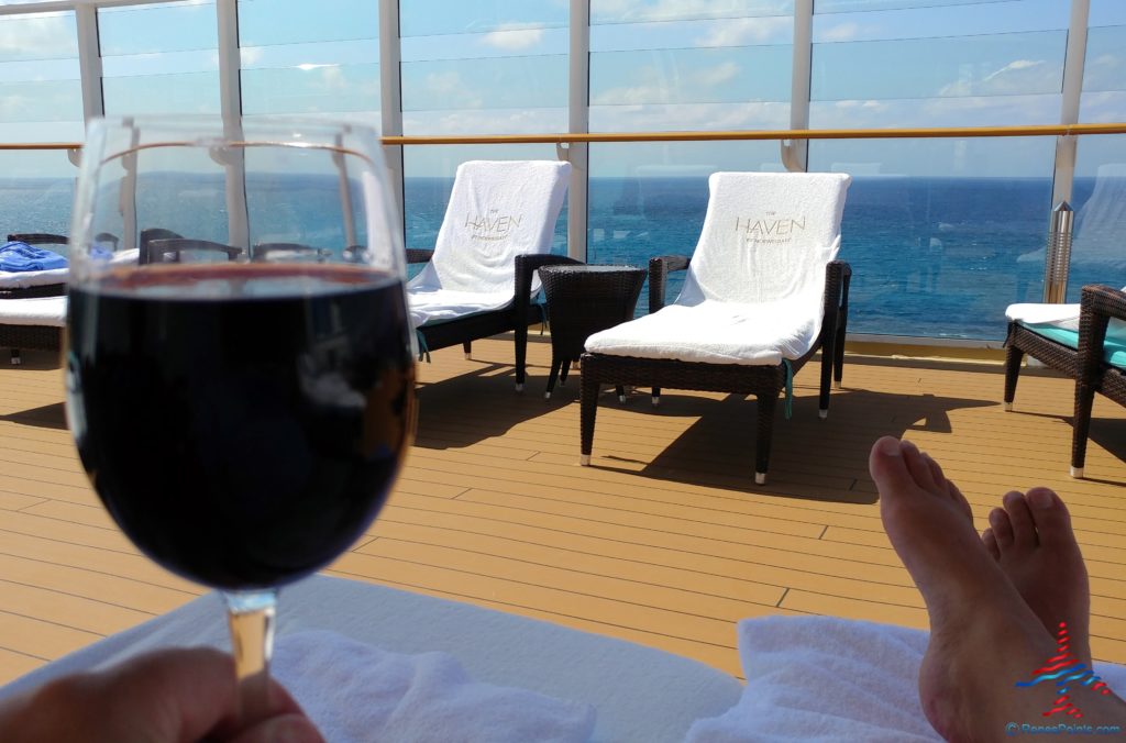 a person holding a glass of wine on a deck of a cruise ship