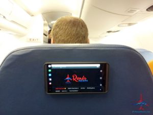 a man sitting in an airplane seat with a smart phone on the back