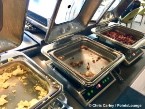 Scrambled eggs, breakfast potatoes, and bacon are seen inside The CLUB at SJC airport lounge at Norman Y. Mineta San Jose International Airport in San Jose, California.