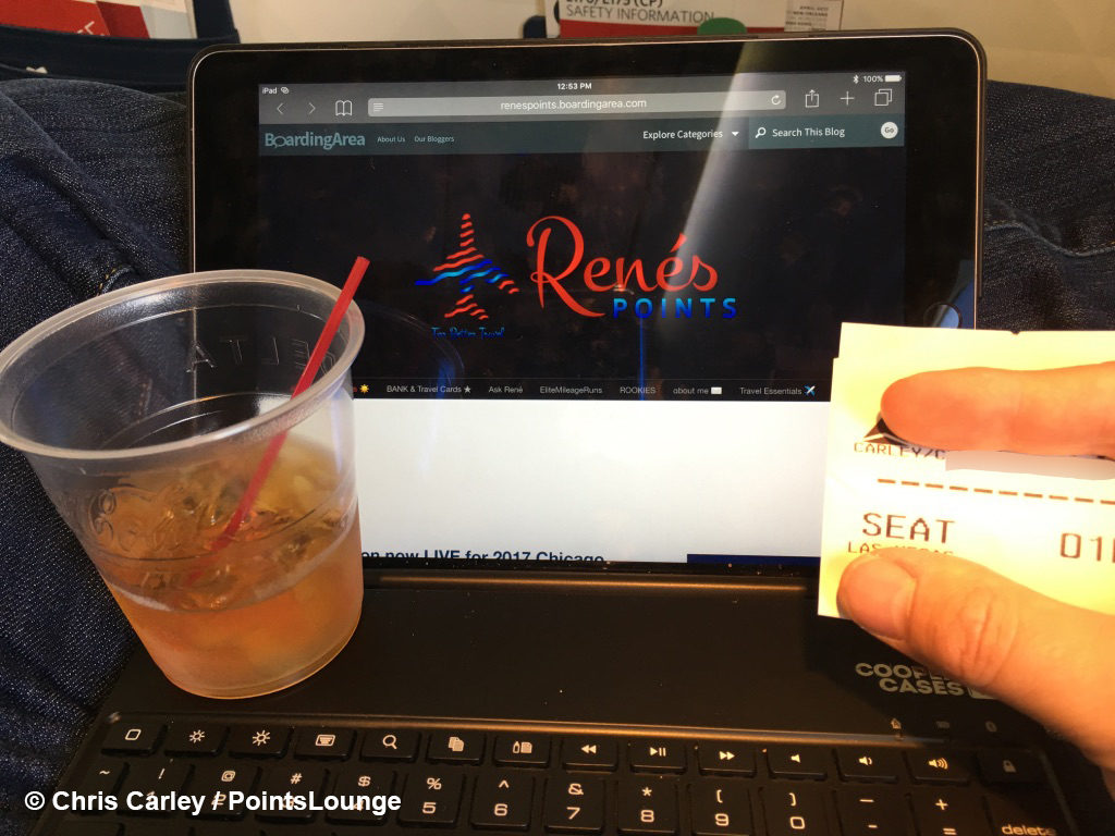 A Delta Air Lines passenger enjoys a Woodford Reserve bourbon whiskey as pre-departure beverage while reading Rene's Points travel blog.