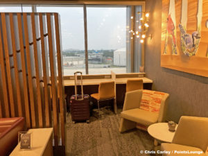 Business cubicles with power outlets and USB ports are seen with a rollaboard suitcase at the Delta Sky Club Austin airport lounge at Austin-Bergstrom International Airport (AUS) in Austin, Texas. Photo © Chris Carley / PointsLounge