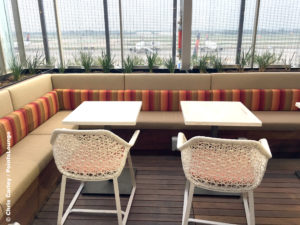 Delta Air Lines (DL) aircraft are seen beyond two tables and chairs on the Sky Deck of the Delta Sky Club Austin airport lounge in Austin, Texas. Photo © Chris Carley / PointsLounge