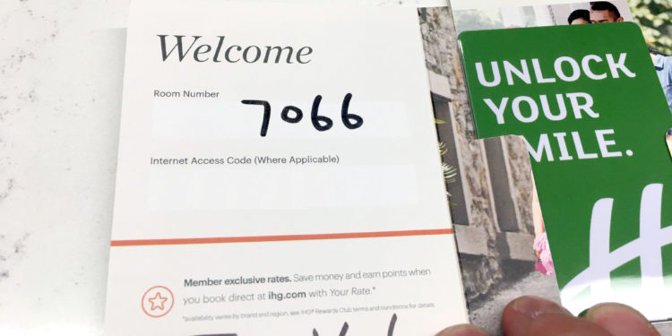 A Holiday Inn hotel key card packet with the room number written inside.
