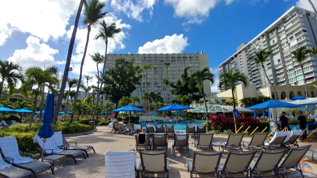 a pool with chairs and umbrellas in front of a hotel