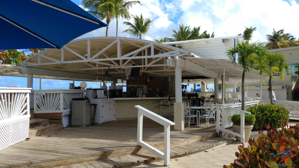 a white building with a blue umbrella and tables