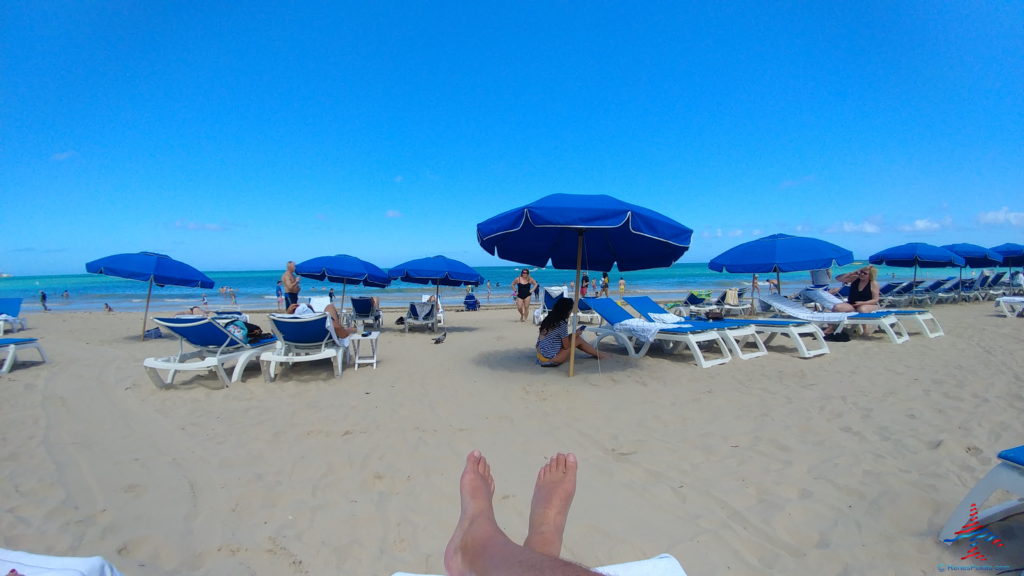 a group of people on a beach with blue umbrellas