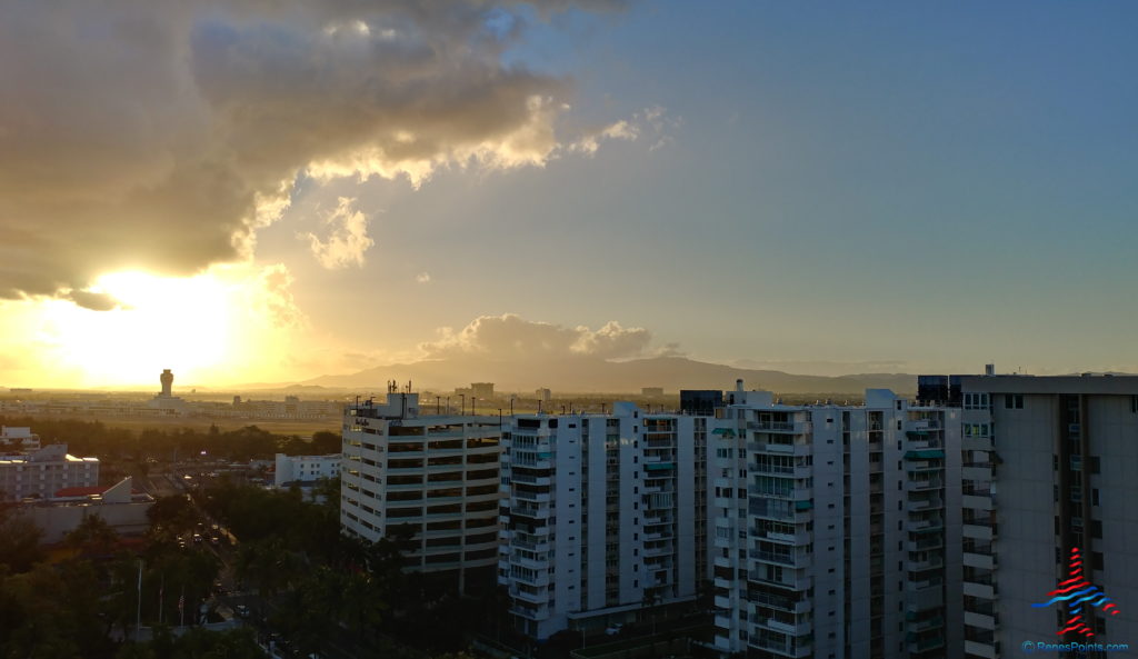 a group of buildings with trees and a sunset