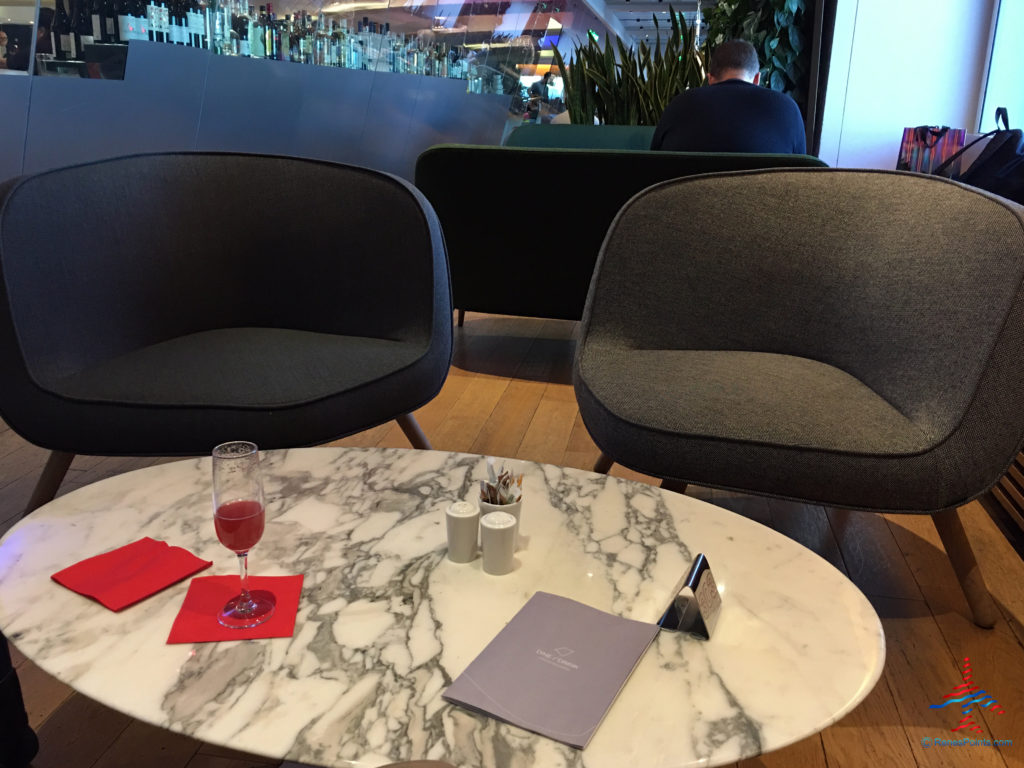 Seating and a Virgin Redhead signature cocktail are seen inside the Virgin Atlantic Clubhouse airport lounge at London Heathrow Airport (LHR).