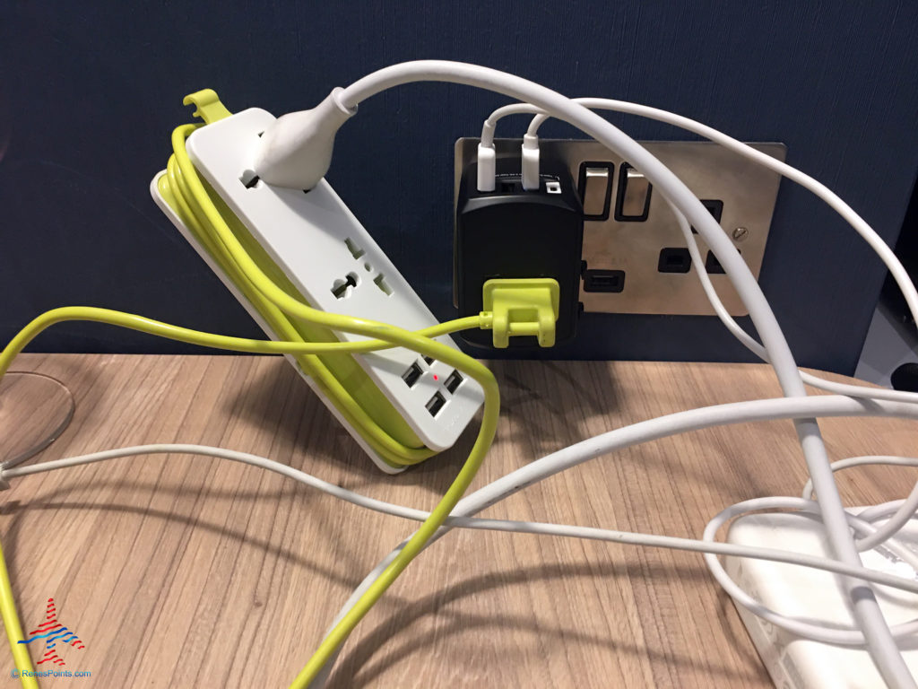 An UPWADE travel power strip surge protector and Gimars travel adapter are seen atop a desk inside a room at the Holiday Inn Express London Heathrow T4 (LHR airport hotel) in Hounslow, United Kingdom.