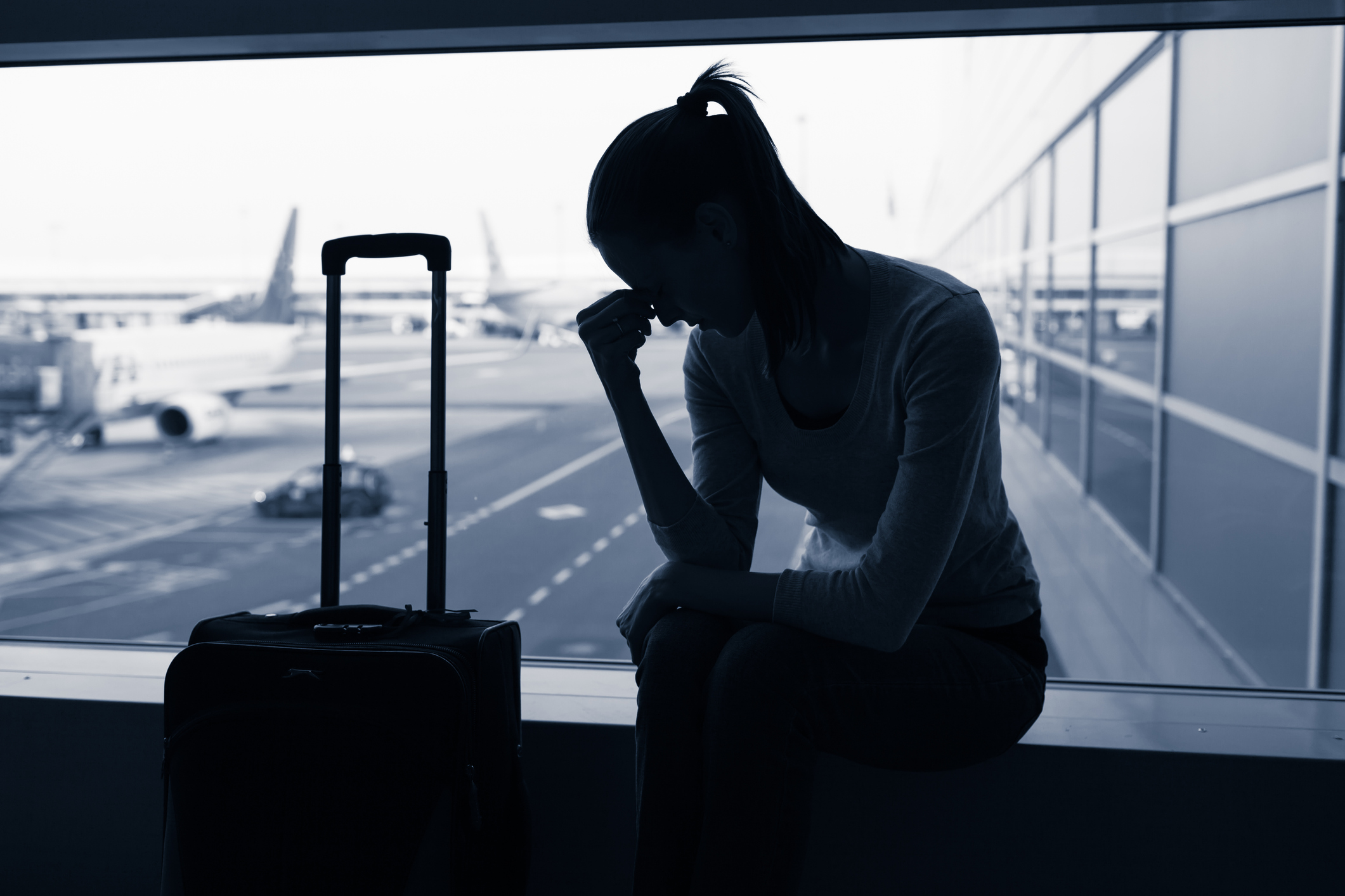 Stressed woman in airport during flight delay.