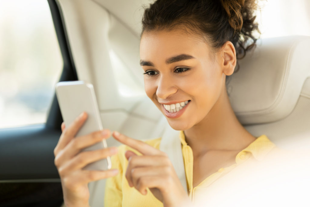 Woman sitting in the backseat of an Uber or Lyft style rideshare car