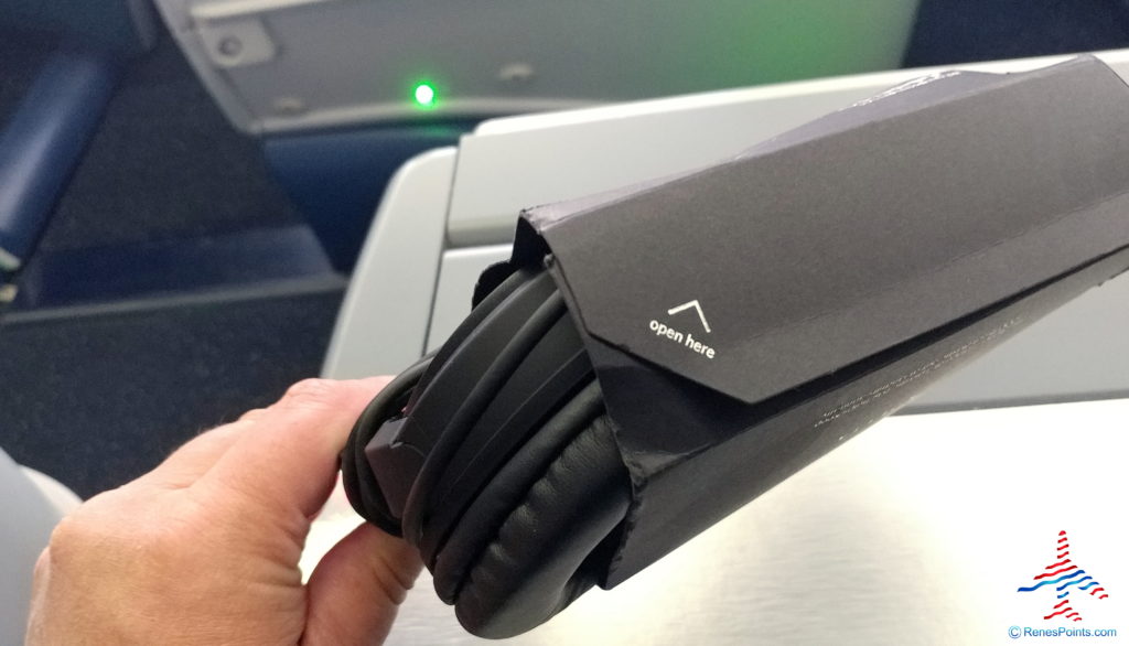 a hand holding a black headphones in a box