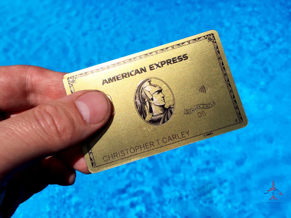 An American Express® Gold Card set against a swimming pool background.