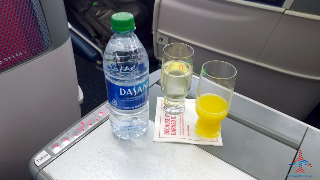 a bottle of water and two glasses of juice on a table