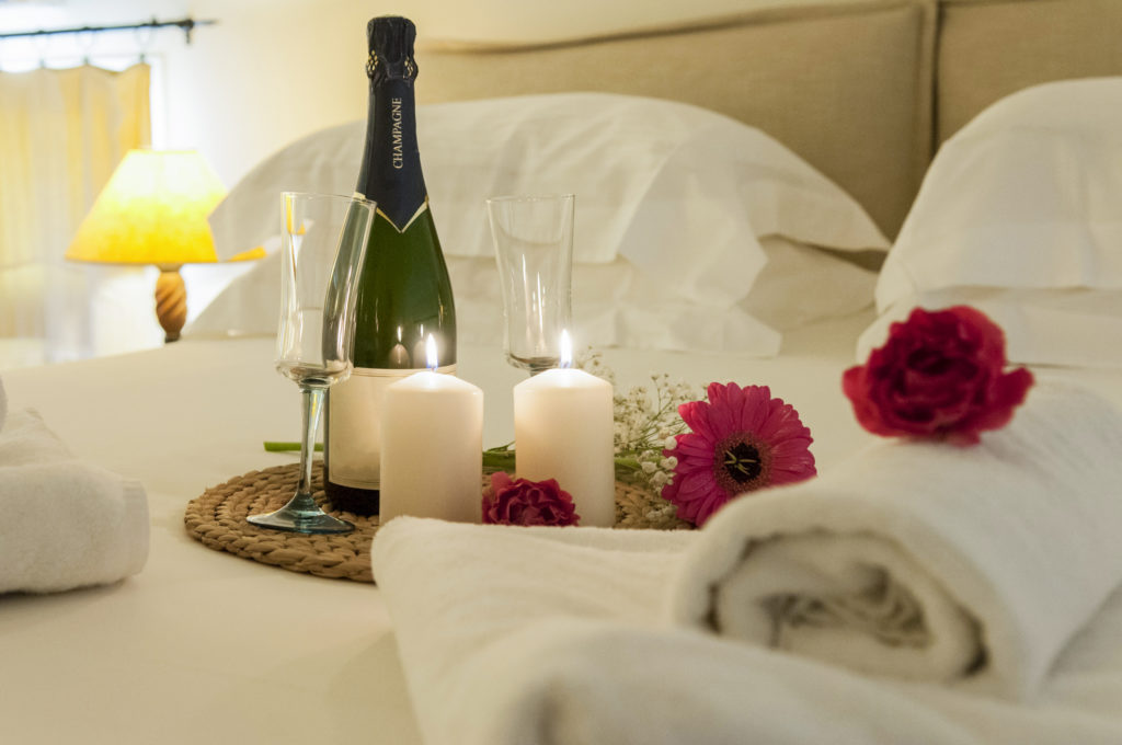 Champagne, flowers, and candles make a romantic setting in a bedroom.