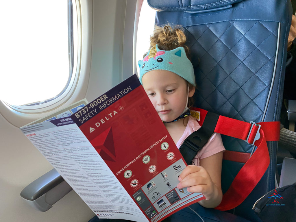 A toddler reads the Delta Air Lines 737-900ER safety card.