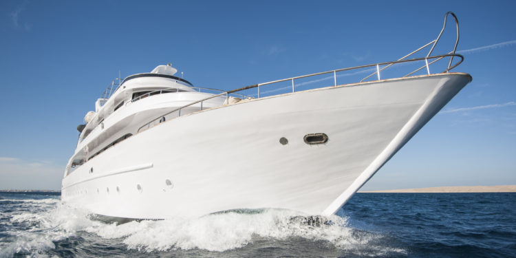 A luxury private motor yacht under way on tropical sea with bow wave