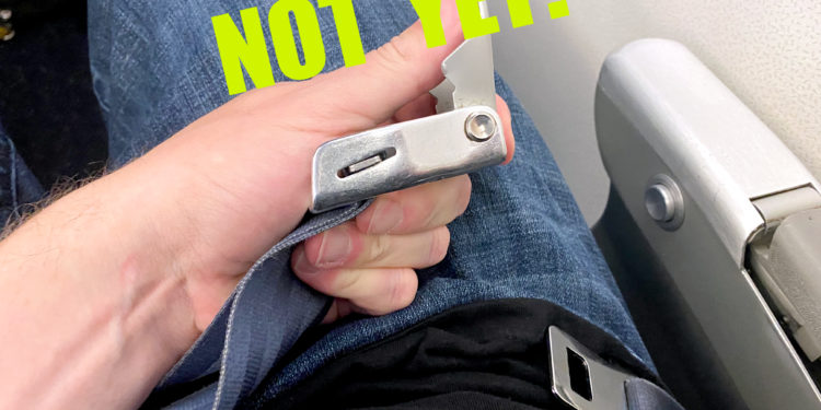 A passenger unbuckles a seatbelt on an airline flight.
