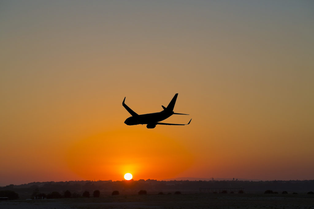 A plane departs into the sunset
