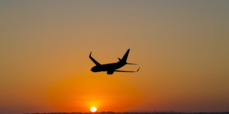 A plane departs into the sunset