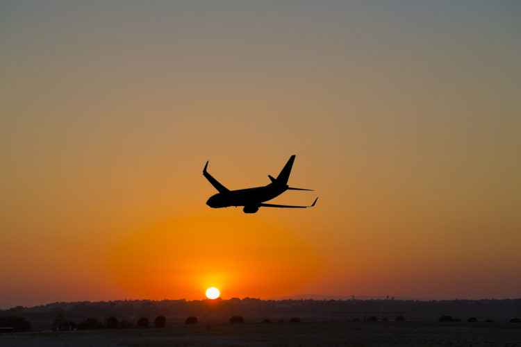 A plane departs into the sunset