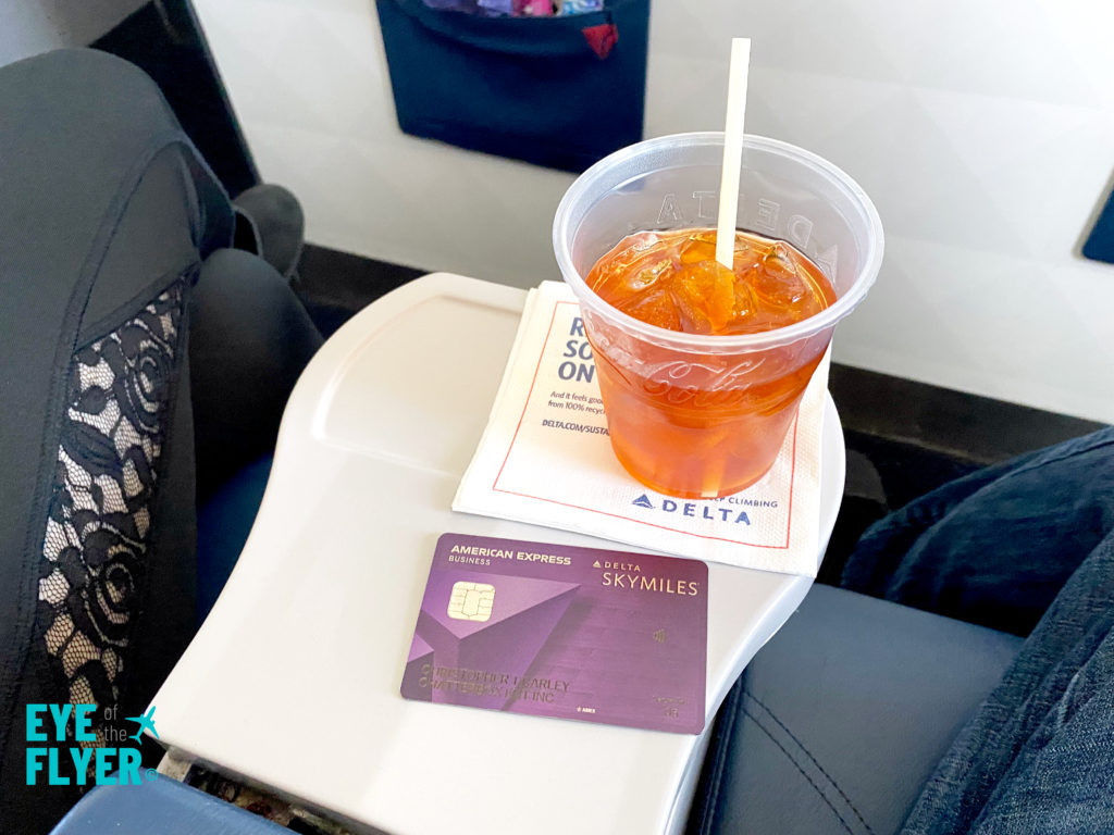 A Delta Reserve card is in seen next to a cocktail enjoyed by first class passengers