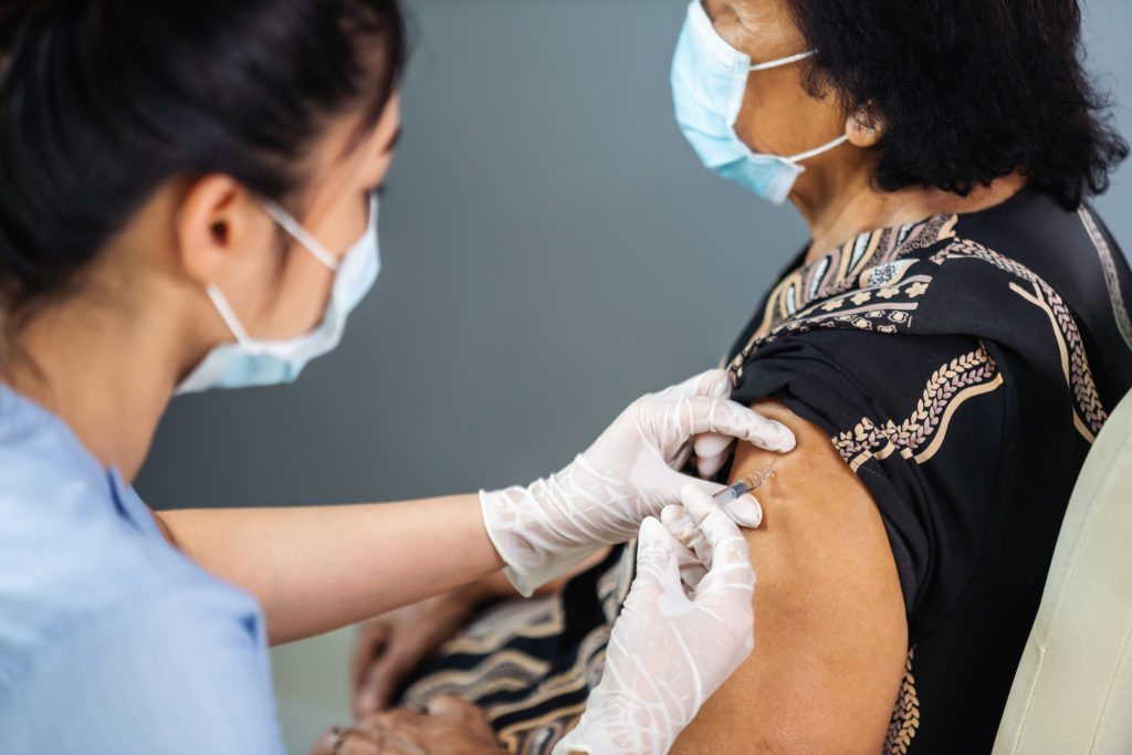 A medical professional gives an injection to a patient.