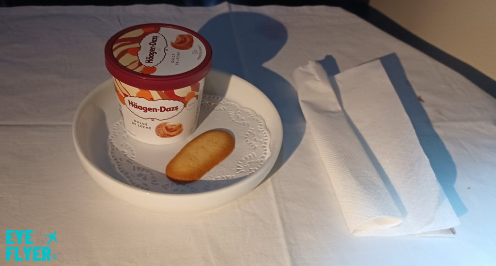 a bowl of ice cream and a biscuit on a white table