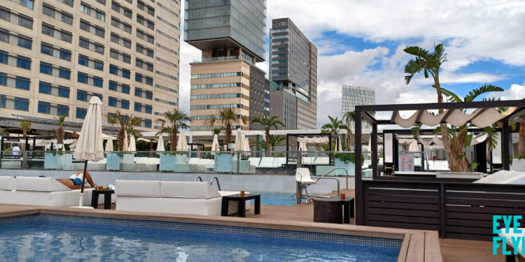 a pool with a deck and chairs in front of a building