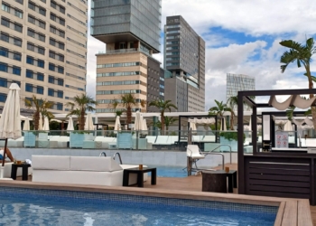 a pool with a deck and chairs in front of a building