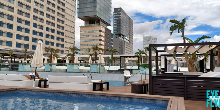 a pool with a deck and chairs in front of a building